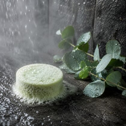 Pastilha de duche verde a dissolver-se em pedra molhada, com eucalipto fresco e vapor