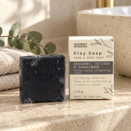 Sabonete de argila preto com a caixa Klay Soap bergamota, vetiver e sândalo numa bancada de casa de banho