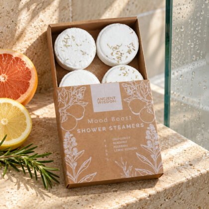Caixa de quatro vapores para o duche Mood Boost Ancient Wisdom numa prateleira do duche com citrinos e alecrim