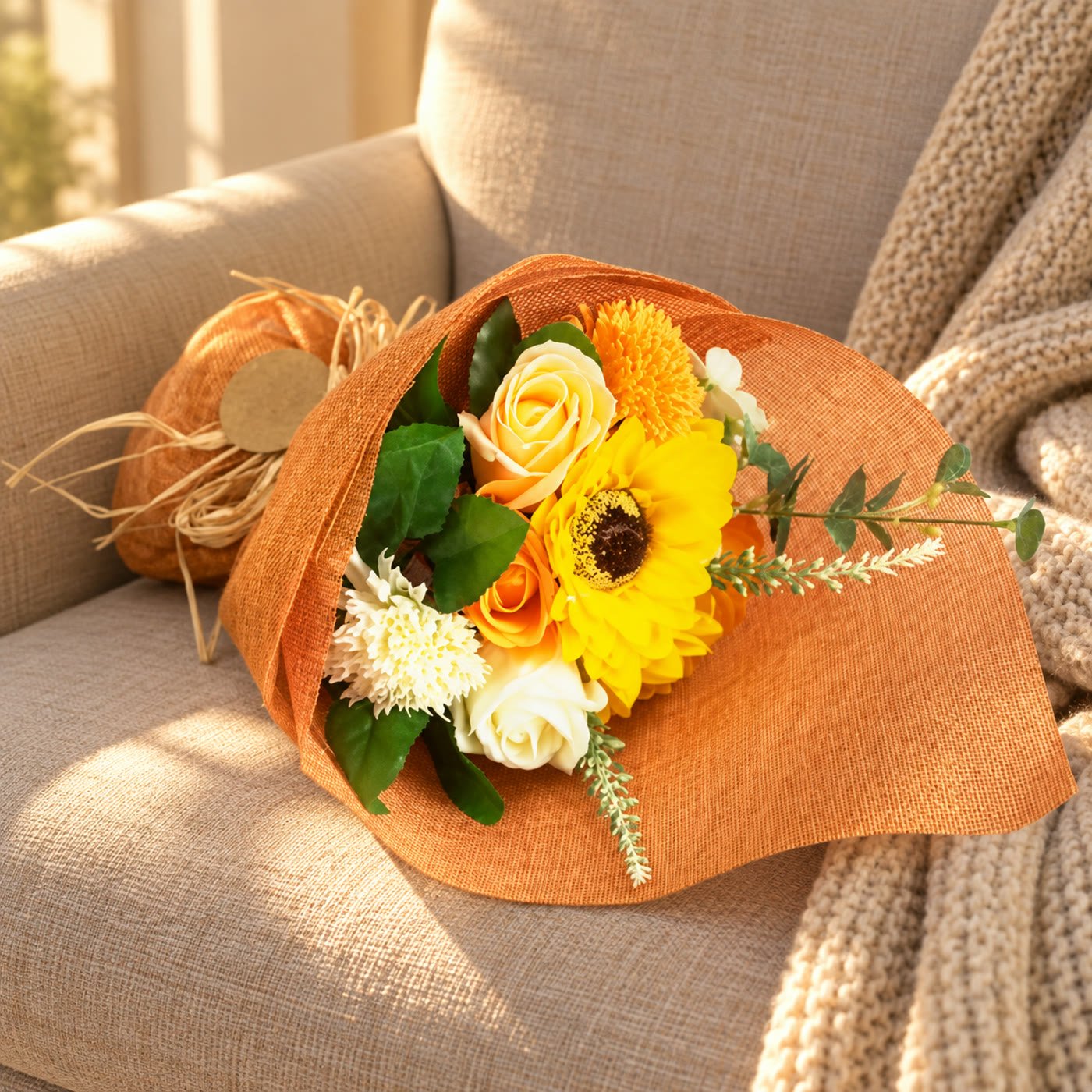 Ramo de flores de sabão laranja e amarelo com girassol pousado num cadeirão de linho com manta