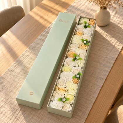 Caixa longa Merci Bouquet com flores de sabão marfim aberta numa mesa de jantar