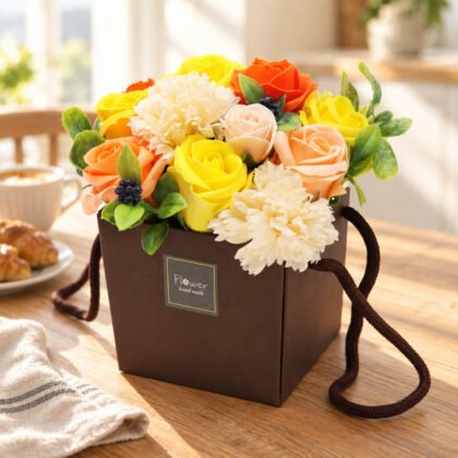 Bouquet de flores de sabão laranja, amarelo e creme num saco castanho Flower hand made numa mesa de pequeno-almoço