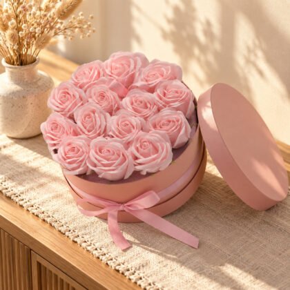 Caixa redonda rosa com rosas de sabão cor-de-rosa e laço num aparador